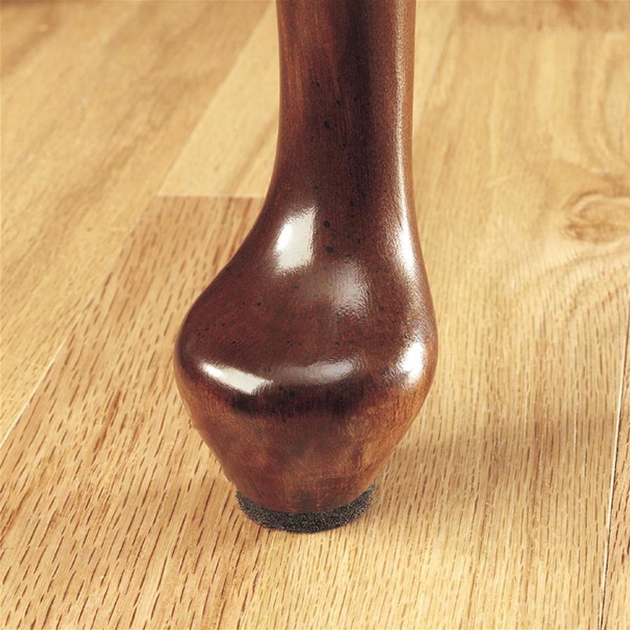 A table leg on a wooden floor with a felt slider under it.